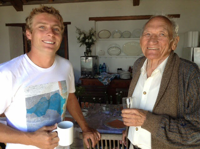 Wilhelm Botha as a young man standing beside his grandfather in a kitchen, both smiling