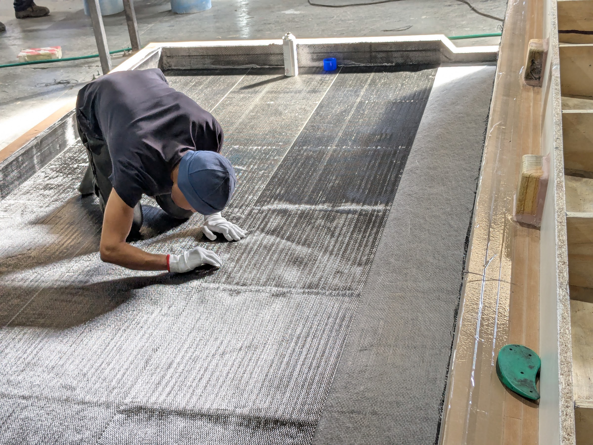 Technician laying carbon fabric by hand inside a large mould