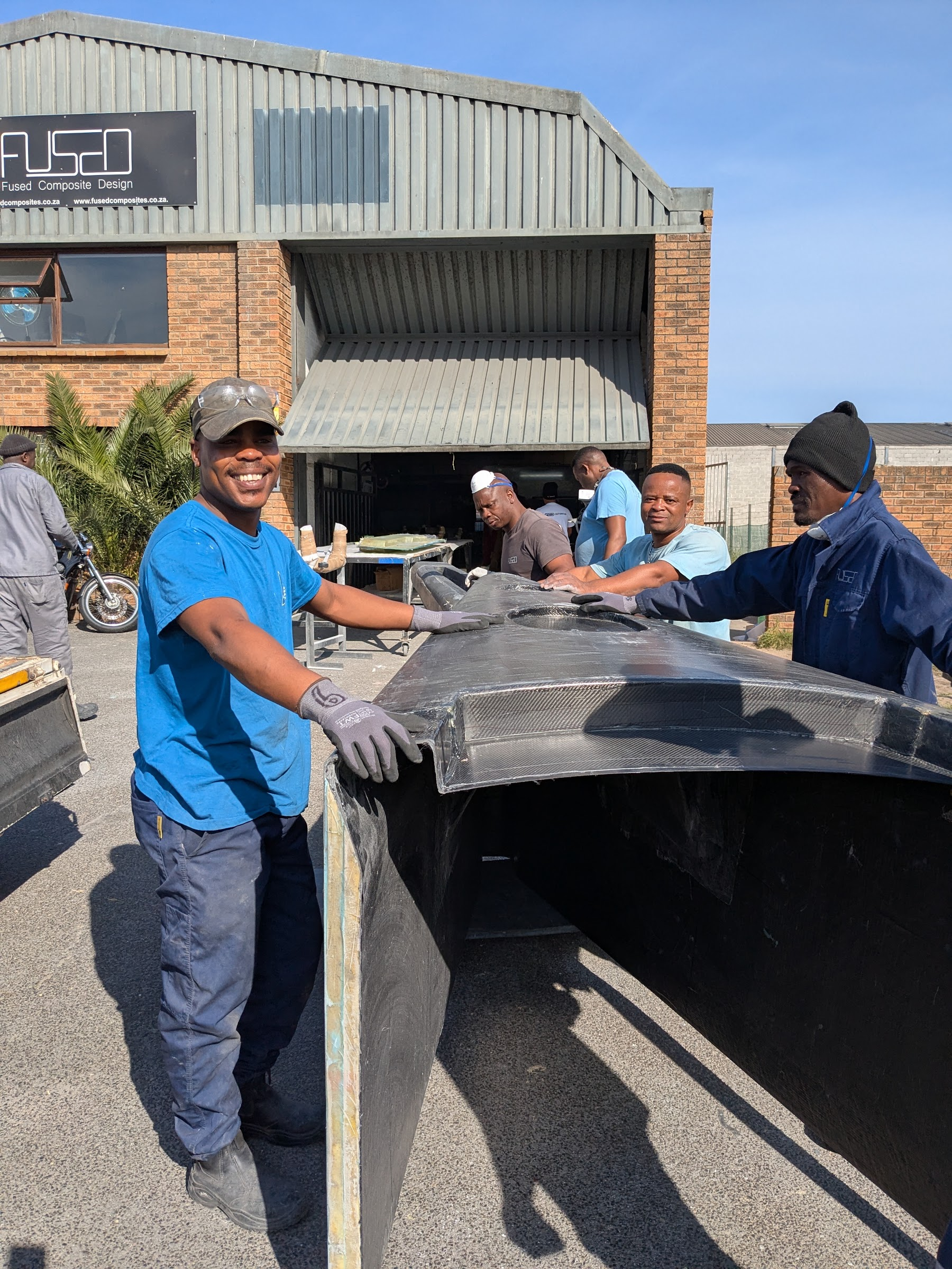 FCD team carrying a finished carbon moulding out of the factory