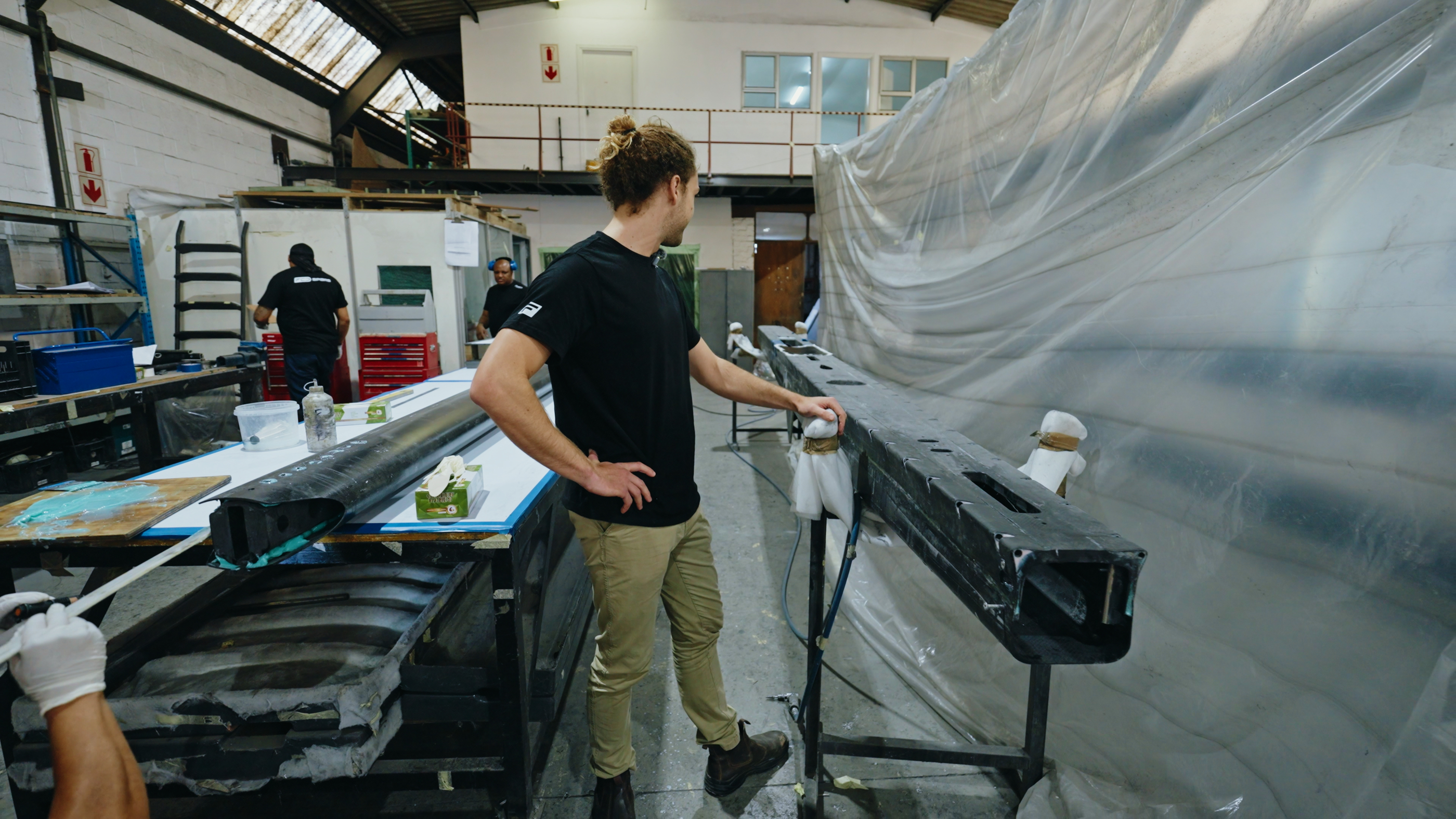 Technician beside a trimmed carbon beam section on trestles in the FCD workshop