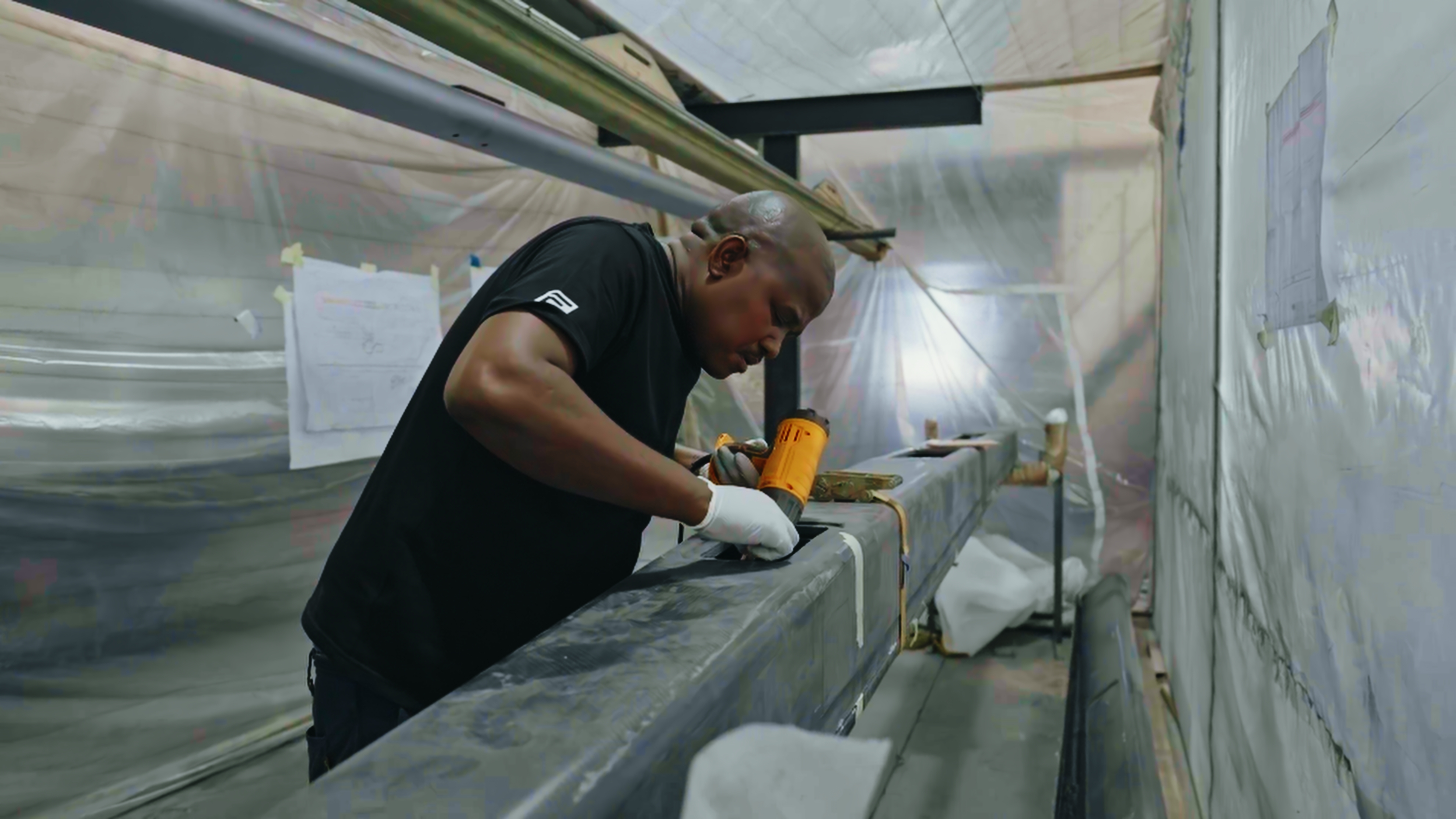 Technician working at a hatch opening on a carbon beam with a heat gun