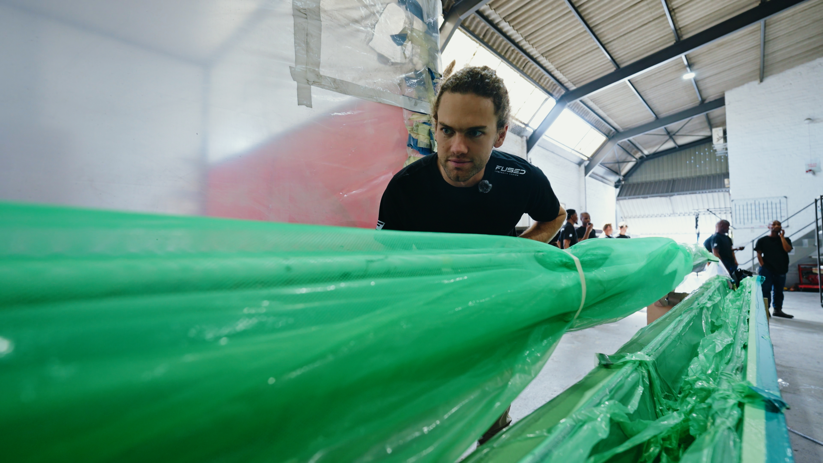 Technician checking a long boom section under green film in the FCD workshop