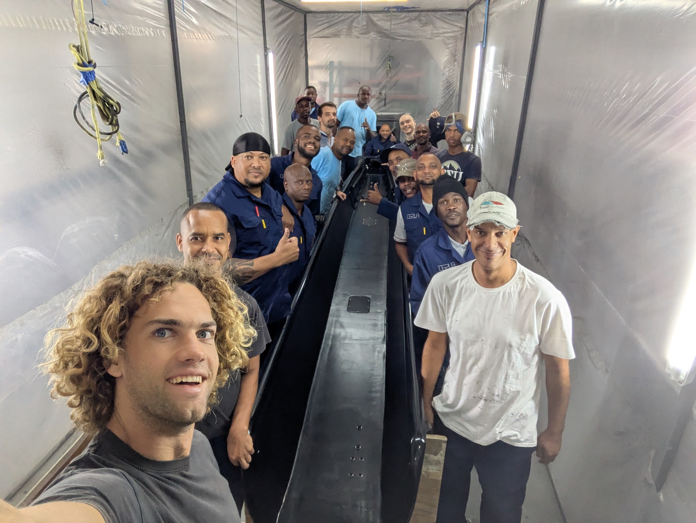 FCD team in the spray booth either side of a finished gloss black furling boom