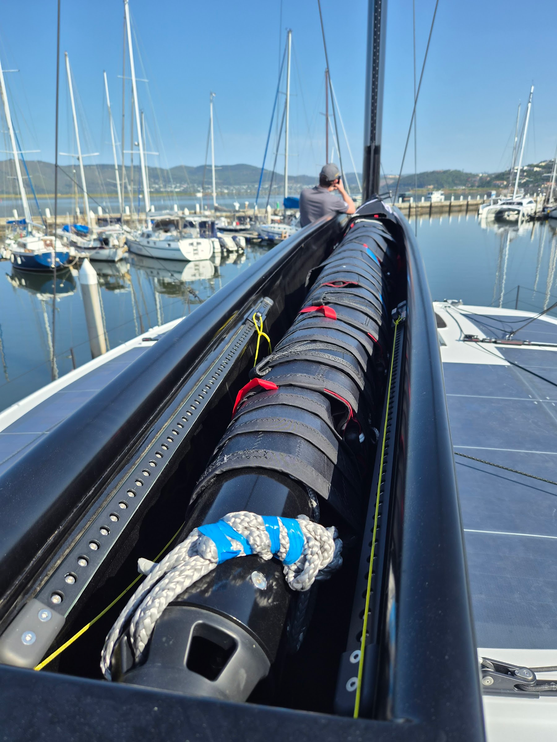 View along the open top of an installed furling boom towards the mast, mandrel and sail inside