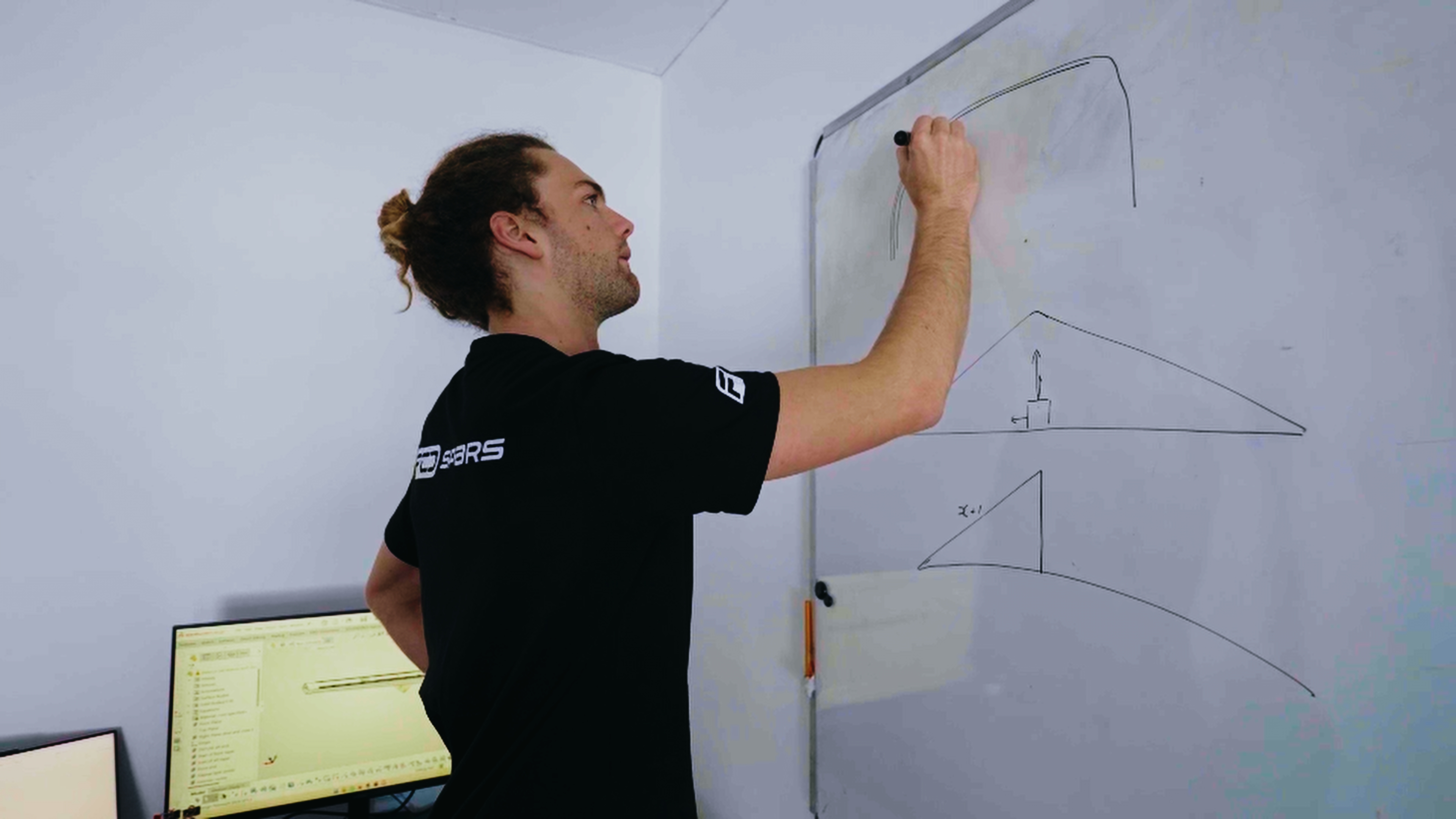 An engineer sketching structural diagrams on a whiteboard