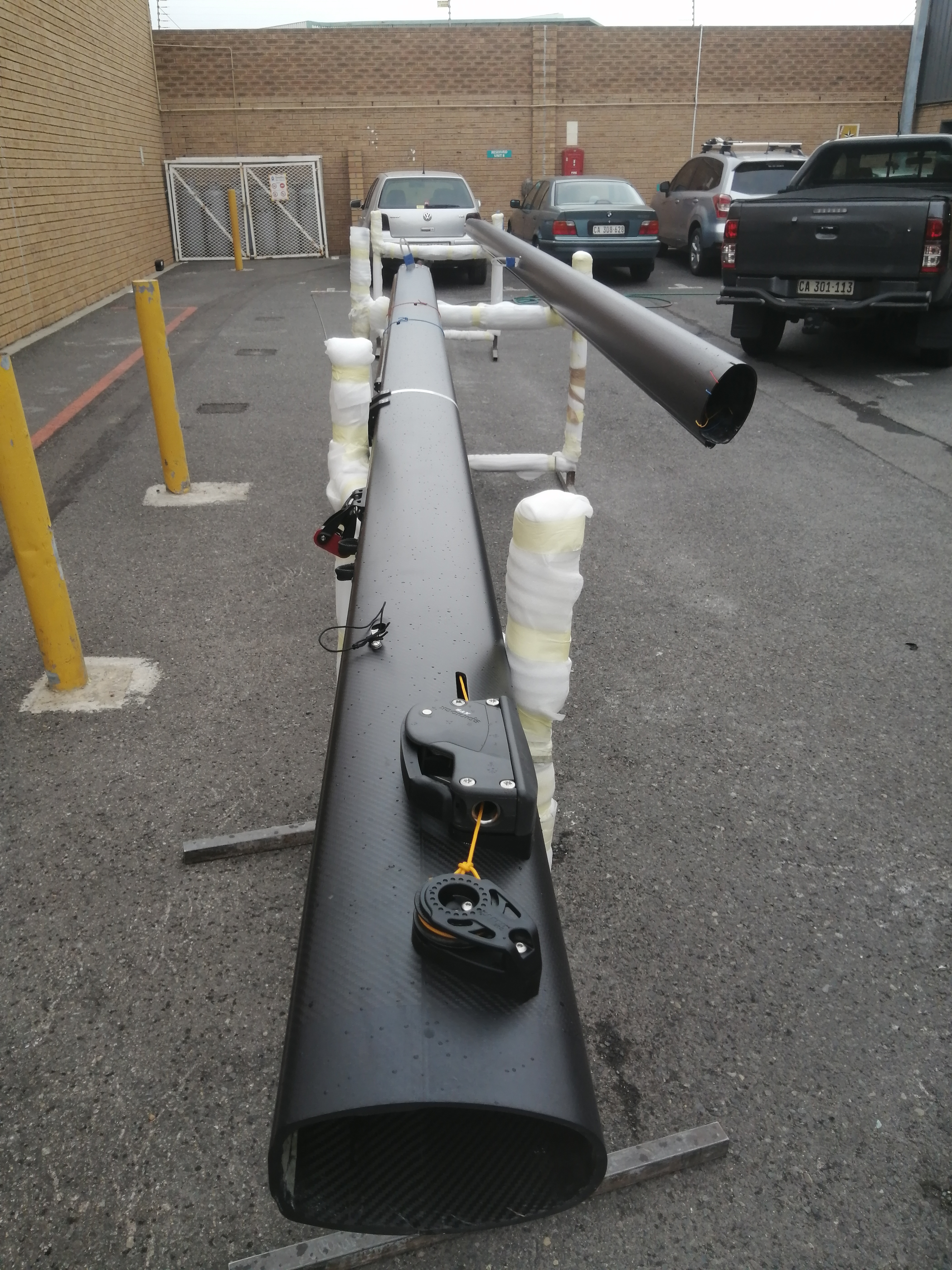Finished carbon mast on trestles outside the factory, wrapped for transport
